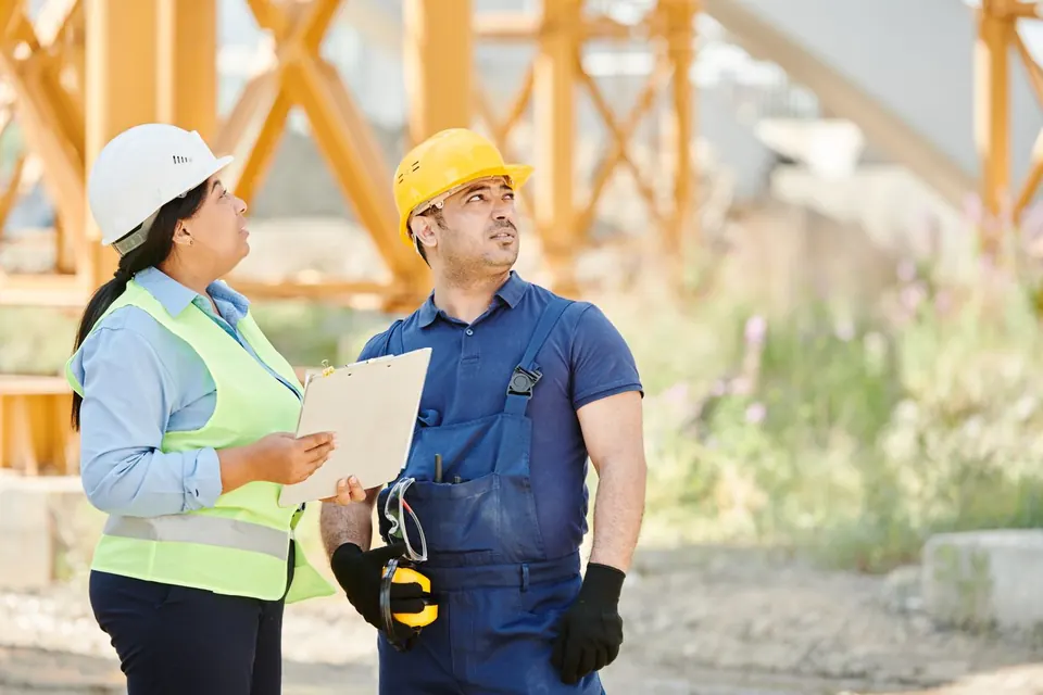 Two construction professionals wearing hard hats discussing work on site